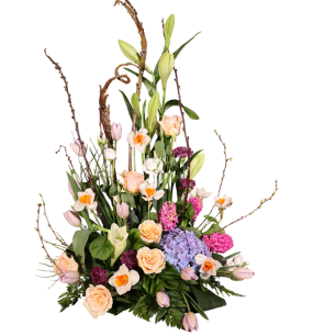 En färgglad blomsterarrangemang med liljor, tulpaner, rosor och hortensior i olika färger som rosa, lila och blå, omgiven av gröna blad och kvistar.