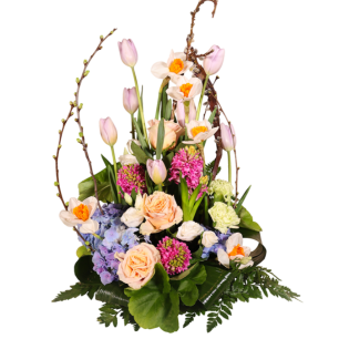 En blomsterarrangemang med rosor, tulpaner, påskliljor och hortensior, omgiven av gröna blad och kvistar.